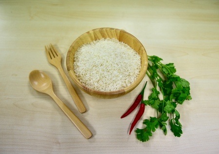 Jasmine rice in wooden bowl,wooden spoon&fork.decoration by chilly pepper & vegetable