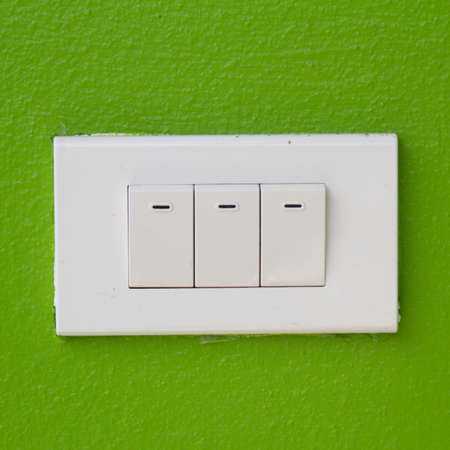 Electrical white rocker light switch on green wallの写真素材