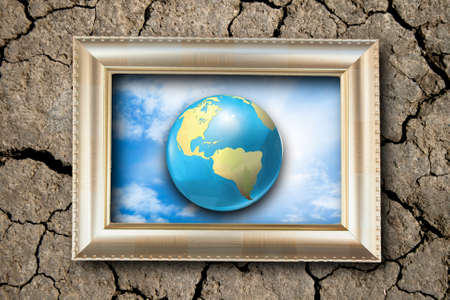 gold color picture frame and earth planet photo on the crack soil backgroundの写真素材