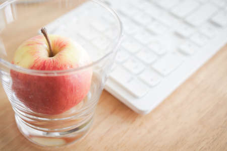 apple on the glass on desk and keyboard backgroundの写真素材