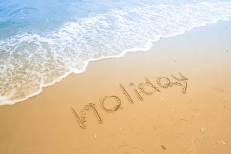 Holiday written in a sandy tropical beachの写真素材