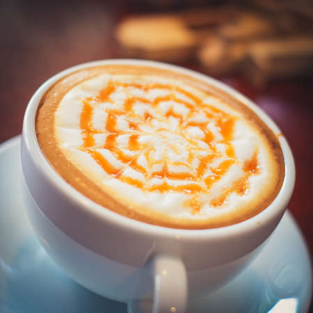 caramel hot coffee on the wooden deskの写真素材