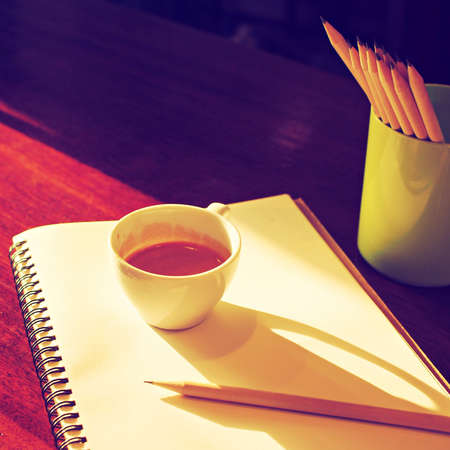 Cup of coffee espresso on the notebook and pencil vintage color toneの写真素材