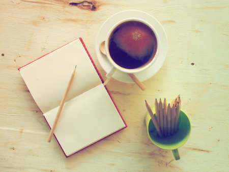 black coffee on the wooden desk with notebook and pencils vintage tone colorの写真素材