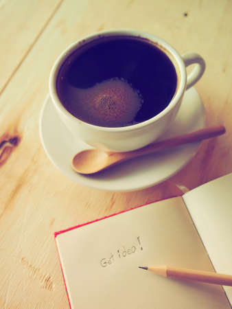 black coffee on the wooden desk with notebook and pencils vintage tone colorの写真素材