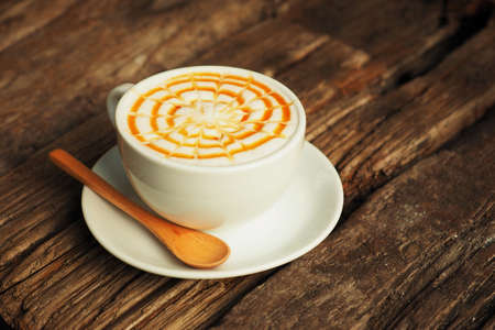 caramel coffee in white cup on wood tableの写真素材