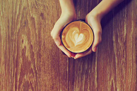 hands holding cup of coffee in coffee shop vintage colorの写真素材