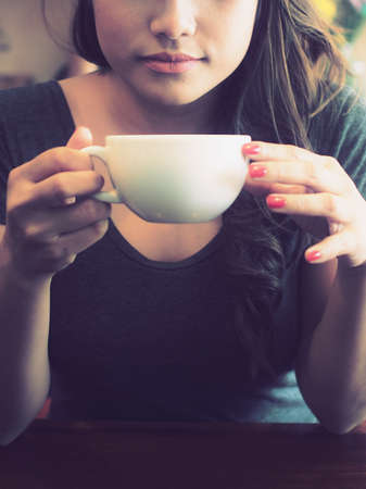 Beautiful Girl Drinking Tea or Coffee in vintage color toned styleの写真素材