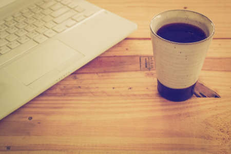 Cup of coffee and laptop on wooden tableの写真素材
