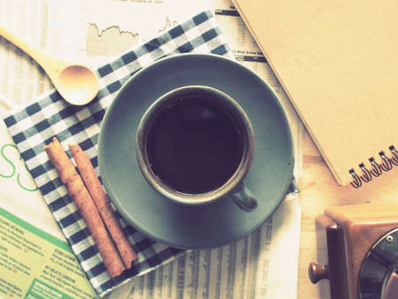 cup of coffee on the wood desk with business newspaper in vintage color tonedの写真素材