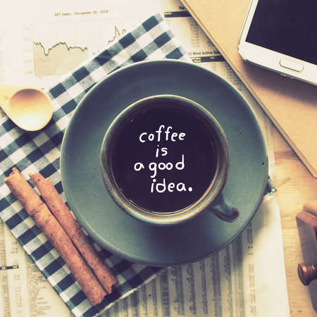 text coffee is a good idea  in cup of coffee on the wood desk with business newspaper in vintage color tonedの写真素材