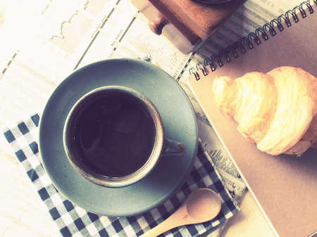 cup of coffee on the wood desk with business newspaper in vintage color tonedの写真素材