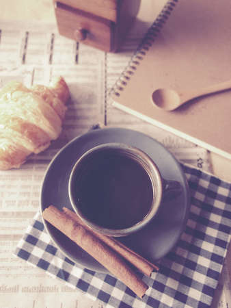 cup of coffee on the wood desk with business newspaper in vintage color tonedの写真素材