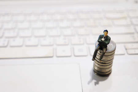miniature businessman sitting on the coin : concept idea about making money with internet e-commerceの写真素材