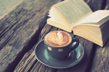 cup of coffee latte art on the wood desk and book in vintage color toneの写真素材