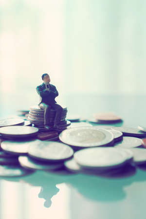 miniature businessman sitting on the coin : concept idea about making money with internet e-commerceの写真素材