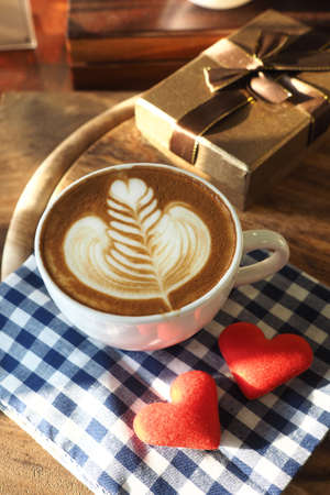 vintage color tone of  cup of coffee with red heart on the table coffee shopの写真素材