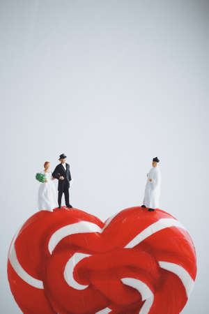 mniature people : groom and bride wedding on heart lollipop white backgroundの写真素材
