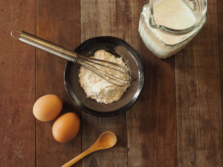 Baking cake ingredients. Bowl, flour, eggs on the wood deskの写真素材