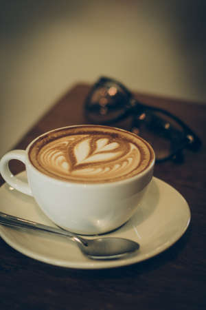 cup of coffee latte art on the wood desk in vintage color toneの写真素材