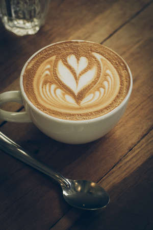 cup of coffee latte art on the wood desk in vintage color toneの写真素材