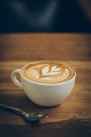 cup of coffee latte art on the wood desk in vintage color toneの写真素材