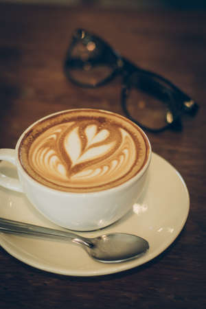 cup of coffee latte art on the wood desk in vintage color toneの写真素材