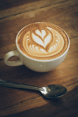 cup of coffee latte art on the wood desk in vintage color toneの写真素材