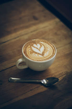 cup of coffee latte art on the wood desk in vintage color toneの写真素材