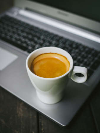 cup of coffee latte on the wood texture with laptop computer in vintage color toneの写真素材