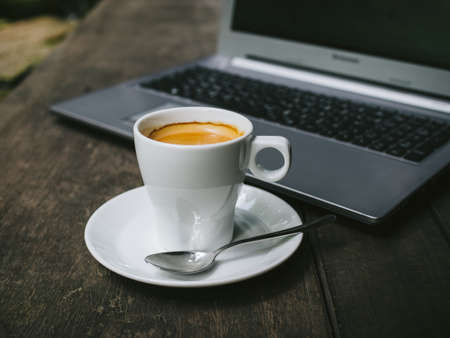 cup of coffee latte on the wood texture with laptop computer in vintage color toneの写真素材
