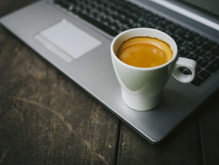cup of coffee latte on the wood texture with laptop computer in vintage color toneの写真素材