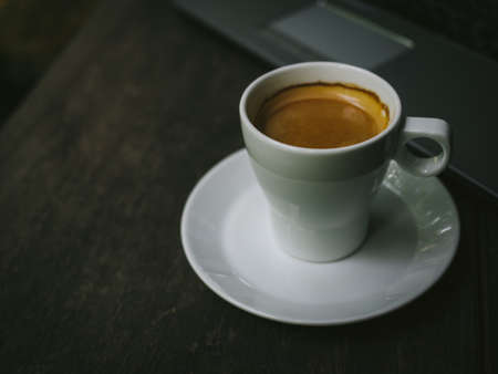 cup of coffee latte on the wood texture with laptop computer in vintage color toneの写真素材