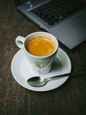 cup of coffee latte on the wood texture with laptop computer in vintage color toneの写真素材