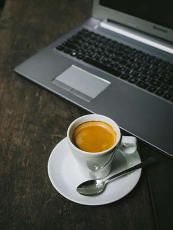cup of coffee latte on the wood texture with laptop computer in vintage color toneの写真素材