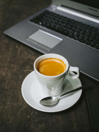 cup of coffee latte on the wood texture with laptop computer in vintage color toneの写真素材