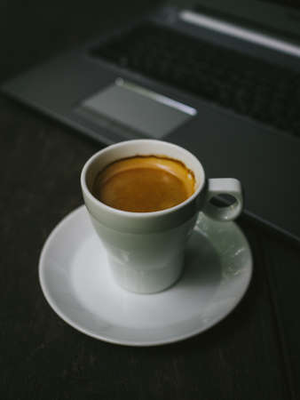cup of coffee latte on the wood texture with laptop computer in vintage color toneの写真素材