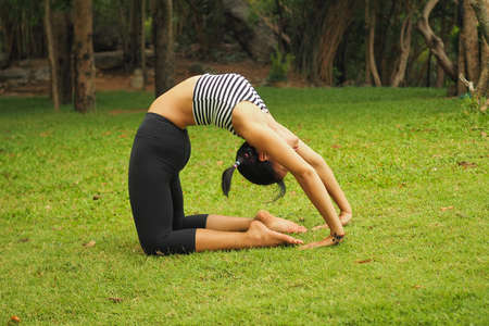 Young woman doing yoga exercises in the garden park