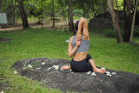 Young woman doing yoga exercises in the garden parkの写真素材