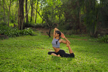 Young woman doing yoga exercises in the garden parkの写真素材