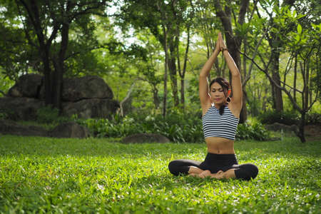 Young woman doing yoga exercises in the garden parkの写真素材