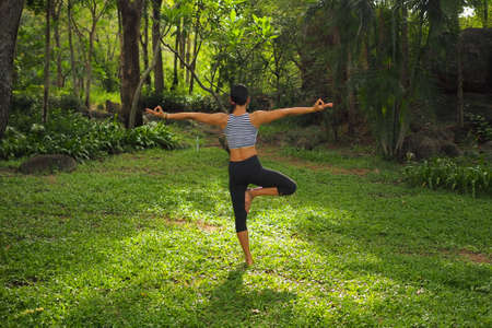 Young woman doing yoga exercises in the garden parkの写真素材