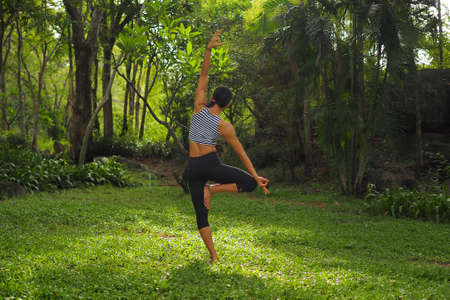 Young woman doing yoga exercises in the garden parkの写真素材