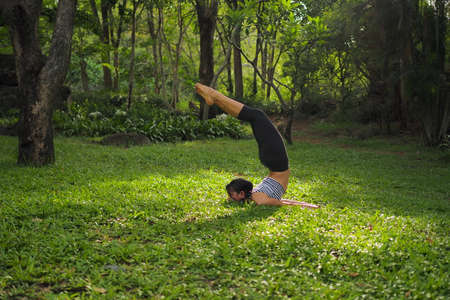 Young woman doing yoga exercises in the garden parkの写真素材