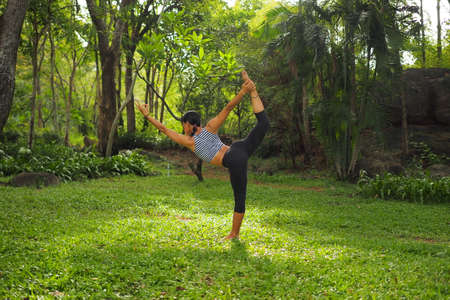 Young woman doing yoga exercises in the garden parkの写真素材