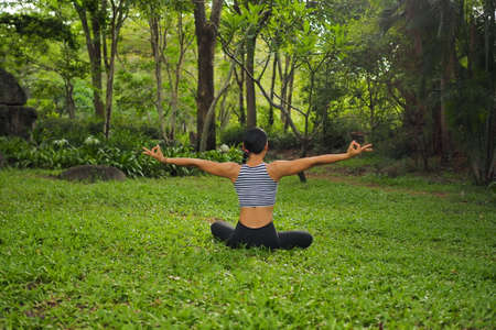 Young woman doing yoga exercises in the garden parkの写真素材
