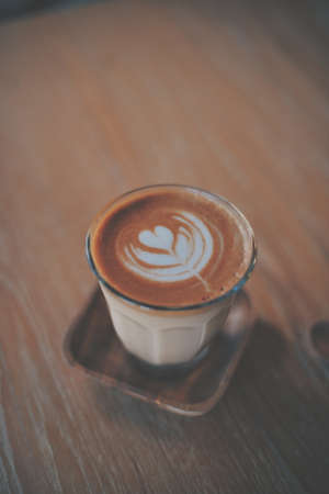 cup of coffee latte on the wood texture   in vintage color toneの写真素材