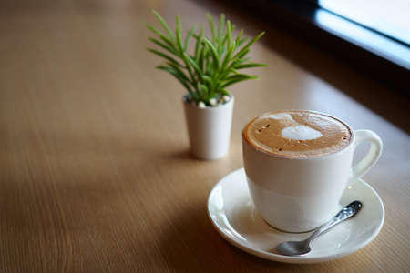 cup of coffee latte art on the wooden desk in coffee shop cafe with vintage color tone filter backgroundの写真素材