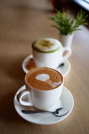 cup of coffee latte art on the wooden desk in coffee shop cafe with vintage color tone filter backgroundの写真素材