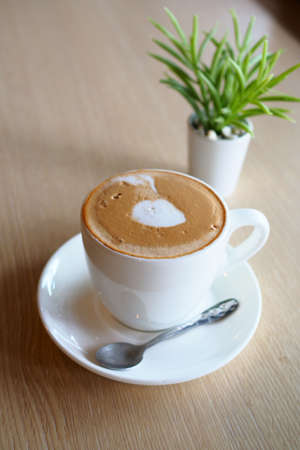 cup of coffee latte art on the wooden desk in coffee shop cafe with vintage color tone filter backgroundの写真素材